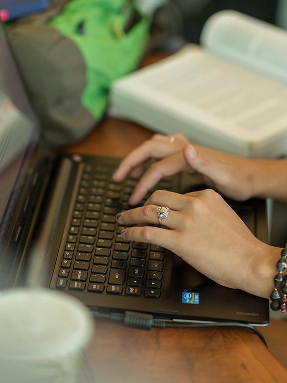 在线学生的手放在笔记本电脑键盘上